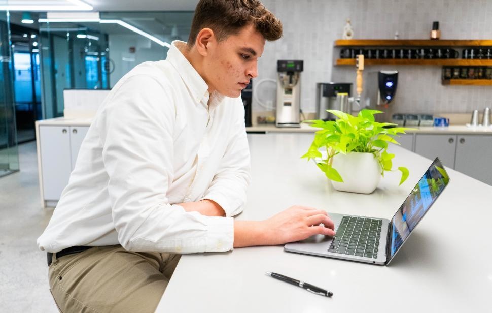 young-man-working-on-laptop-with-plant-on-table-in-kitchen-area.jpg